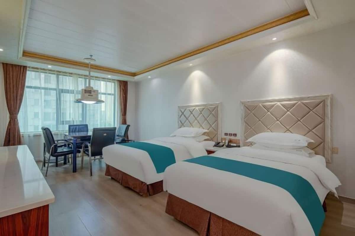 Una habitación de hotel con dos camas, un escritorio y una silla.
