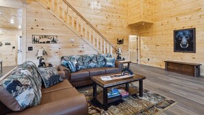 Un interior de madera con una escalera, un conjunto de sofás, una mesa de centro y un cuadro en la pared.