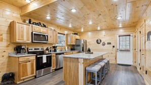 Cocina de cabaña de madera con una isla central, electrodomésticos de acero inoxidable y decoración temática de osos.