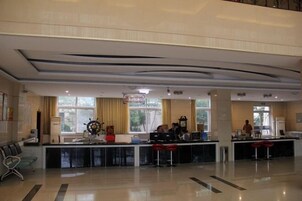 A spacious lobby with a reception desk, seating area, and large windows.