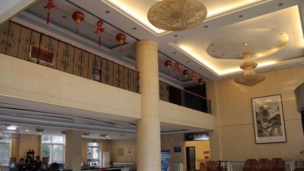 A spacious lobby with a high ceiling, decorative lanterns, and a large column. - Seamens Club (Longkou)