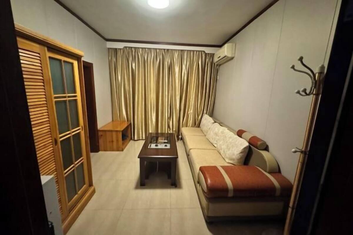 A living room with a sofa, a coffee table, a wooden cabinet, and a curtain.