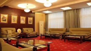 A hotel room with a red carpet, four sofas, two coffee tables, and three wall-mounted lamps. - Seamens Club (Longkou)