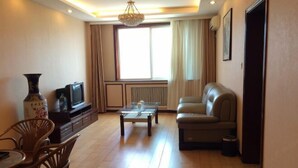 A living room with a sofa, a coffee table, a TV, and a vase. - Seamens Club (Longkou)