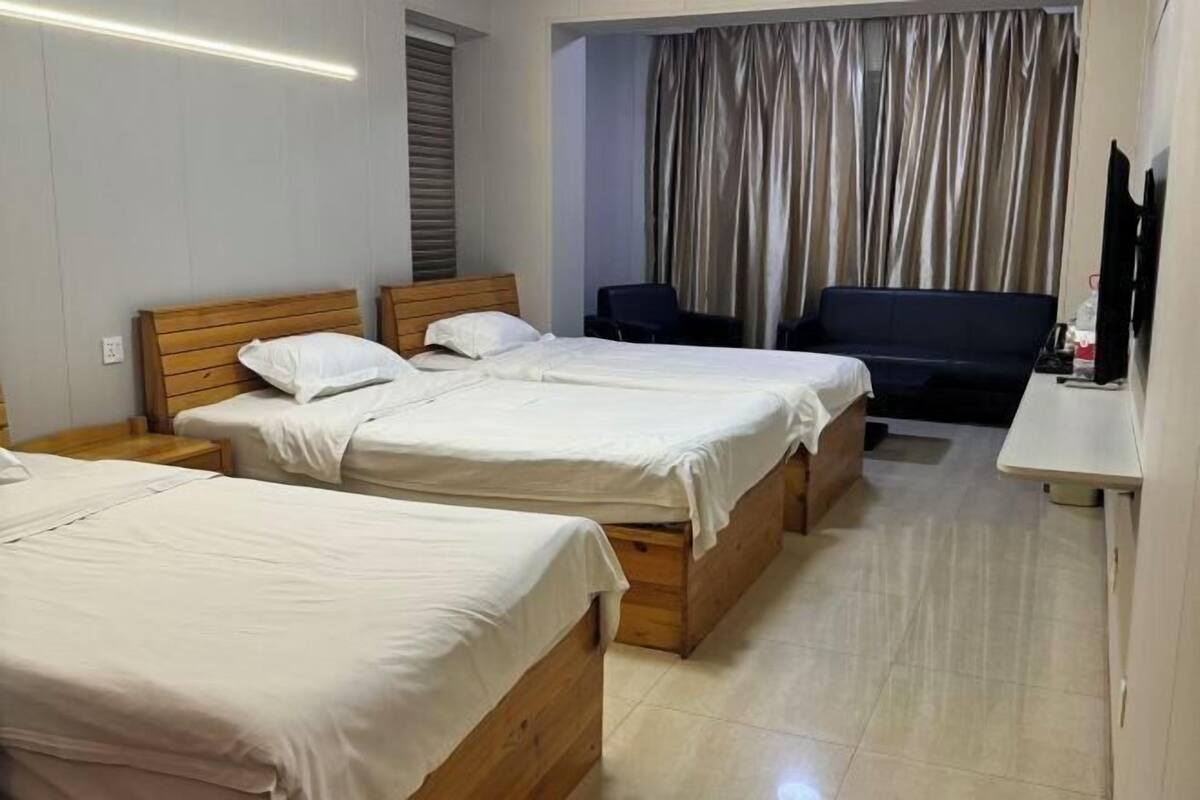 A hotel room with two wooden beds, a desk, a chair, and a television.