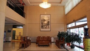 A spacious lobby with a high ceiling, a large chandelier, wooden furniture, and a large painting on the wall. - Seamens Club (Longkou)