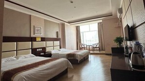 Ein Hotelzimmer mit zwei Betten, einem Esstisch, Stühlen, einem Fernseher und einer Kaffeemaschine.