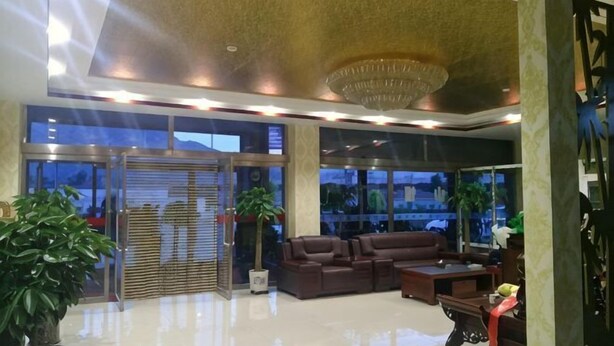 Eine Lobby mit Empfangsschalter, Sitzgelegenheiten, großen Fenstern und einem Chandelier.