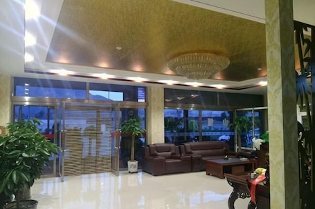 A lobby with a reception desk, seating area, large windows, and a chandelier.. Hunyuan Haoya Express Hotel
