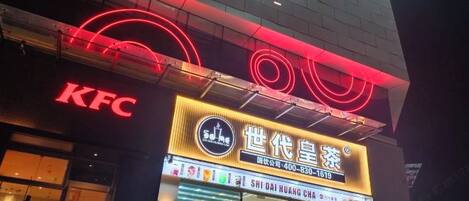 A KFC restaurant with neon signage and a traditional Chinese tea shop sign above it.