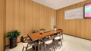 A conference room with a wooden table, chairs, a potted plant, and a map on the wall. - Shankee Hotel (Shenzhen International Exhibition Center Haoxiang Subway Station) (Shenzhen)