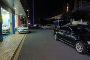 Un'area di parcheggio notturna con auto parcheggiate lungo il lato di un edificio.