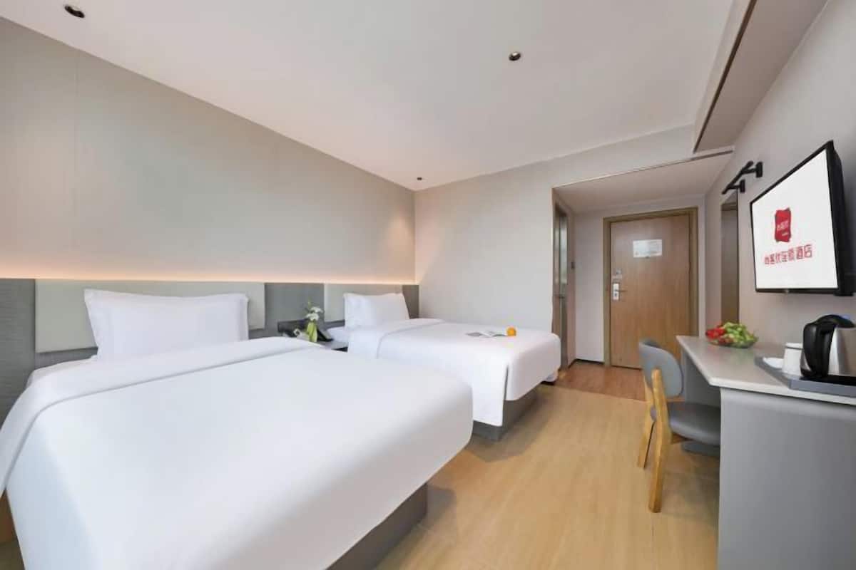 A hotel room with two beds, a desk, and a chair.