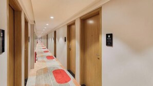 A hotel corridor with wooden doors, numbered room signs, and a patterned carpet. - Shankee Hotel (Shenzhen International Exhibition Center Haoxiang Subway Station) (Shenzhen)