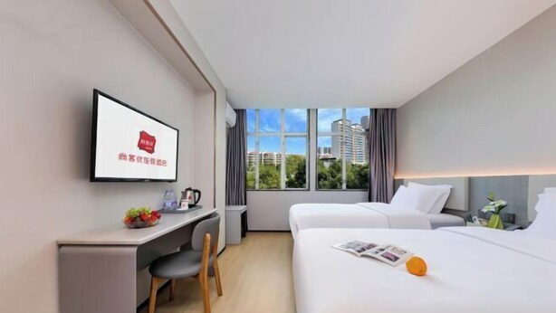 A hotel room with a bed, a desk, a chair, a TV, and a window with a city view. - Shankee Hotel (Shenzhen International Exhibition Center Haoxiang Subway Station) (Shenzhen)