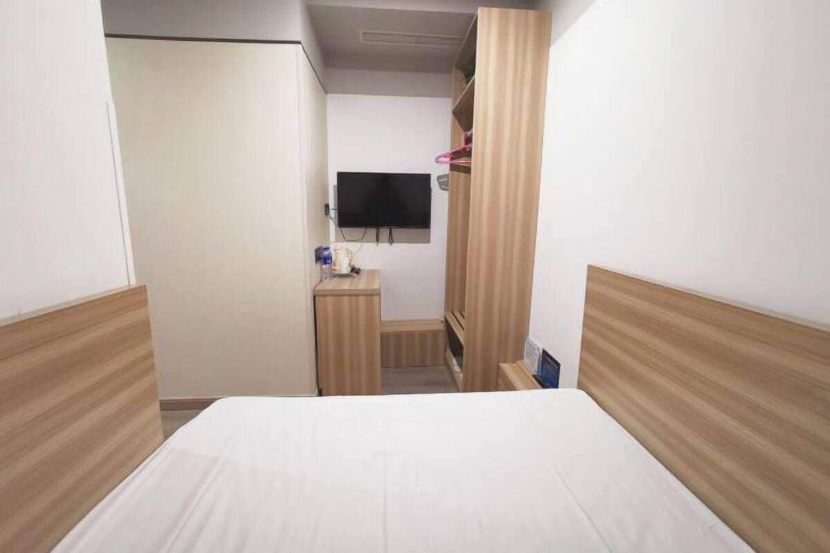 A hotel room with a bed, a wardrobe, a television, and a small desk.