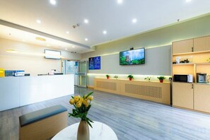 A modern reception area with a reception desk, seating, a flat-screen TV, and a decorative vase with flowers. - Homeinn Pebble Hotel (Beijing Tongren Hospital Chongwenmen Subway Station) (Beijing)