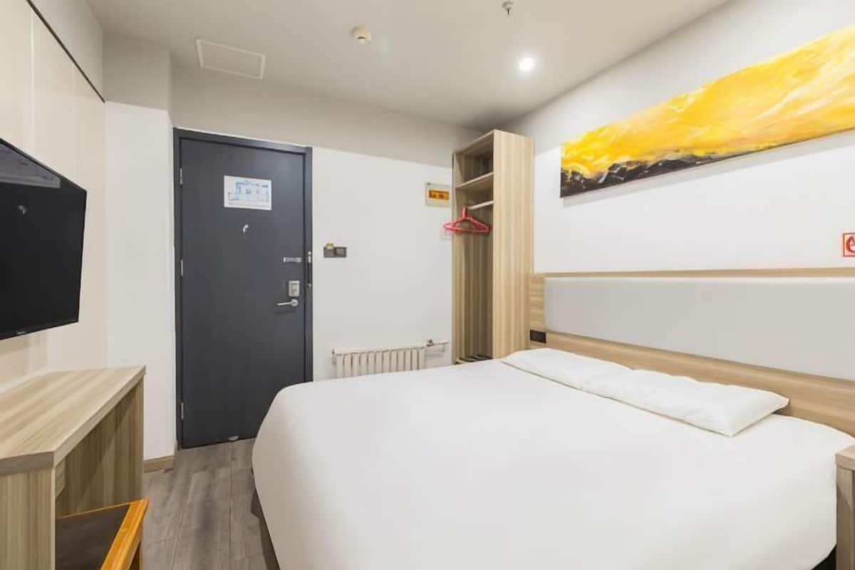 Une chambre d’hôtel équipée d’un lit, d’une télévision, d’une armoire et d’un porte-manteau.