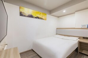 A hotel room with a bed, a painting on the wall, a bedside table, and a wooden nightstand. - Homeinn Pebble Hotel (Beijing Tongren Hospital Chongwenmen Subway Station) (Beijing)