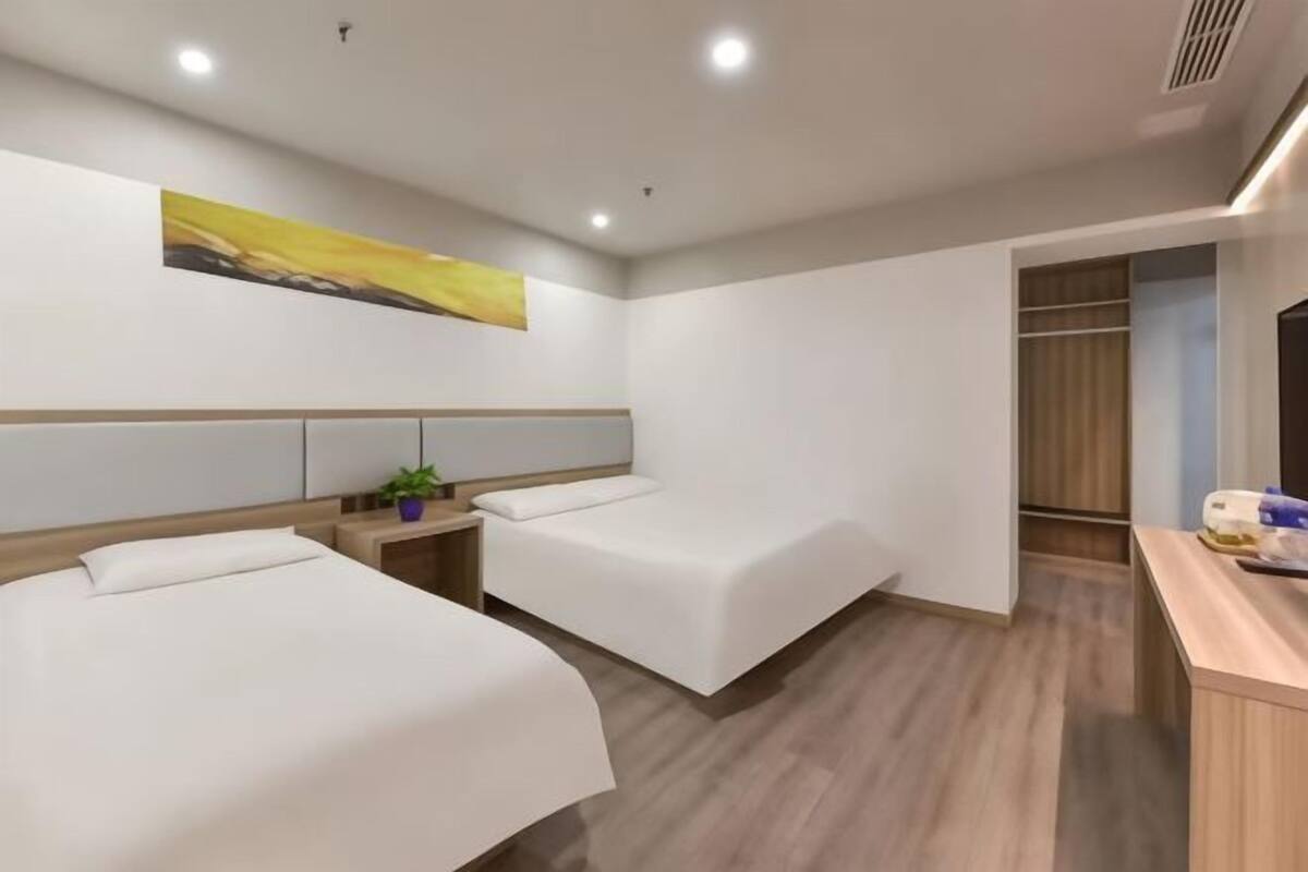 Une chambre d’hôtel avec deux lits, un bureau, une télévision et une armoire.
