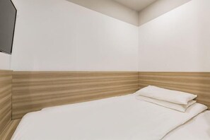 A corner bedroom with a wooden headboard, a white bedspread, and a flat-screen TV mounted on the wall. - Homeinn Pebble Hotel (Beijing Tongren Hospital Chongwenmen Subway Station) (Beijing)