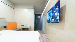 Ein Hotelzimmer mit Bett, Schreibtisch, Stuhl, Fernseher und einer Tür.
