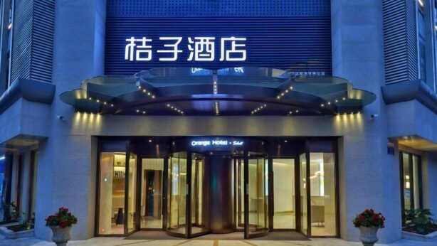 A hotel entrance with a revolving door, glass facade, and signage for "Orange Hotel". - Orange Hotel (Chengdu Huanhuaxi) (Chengdu)
