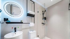 A modern bathroom with a white sink, toilet, and shower. There is a mirror with a light above it and a towel rack. - Qingji Hotel MINI (Shanghai Overseas Gaoqiao Guangming Road Branch) (Shanghai)