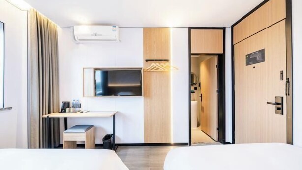 A modern hotel room with a desk, two beds, a mirror, and a wardrobe. - Qingji Hotel MINI (Shanghai Overseas Gaoqiao Guangming Road Branch) (Shanghai)