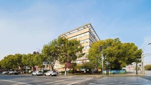 A modern building with a unique angular design, surrounded by trees and parked cars. - Qingji Hotel MINI (Shanghai Overseas Gaoqiao Guangming Road Branch) (Shanghai)