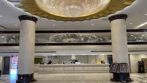 A lobby with a reception desk, two large columns, a chandelier, and a patterned floor. - Beijing Jindilai Business Club (Yansai Outlets Miyun Branch) (Beijing)