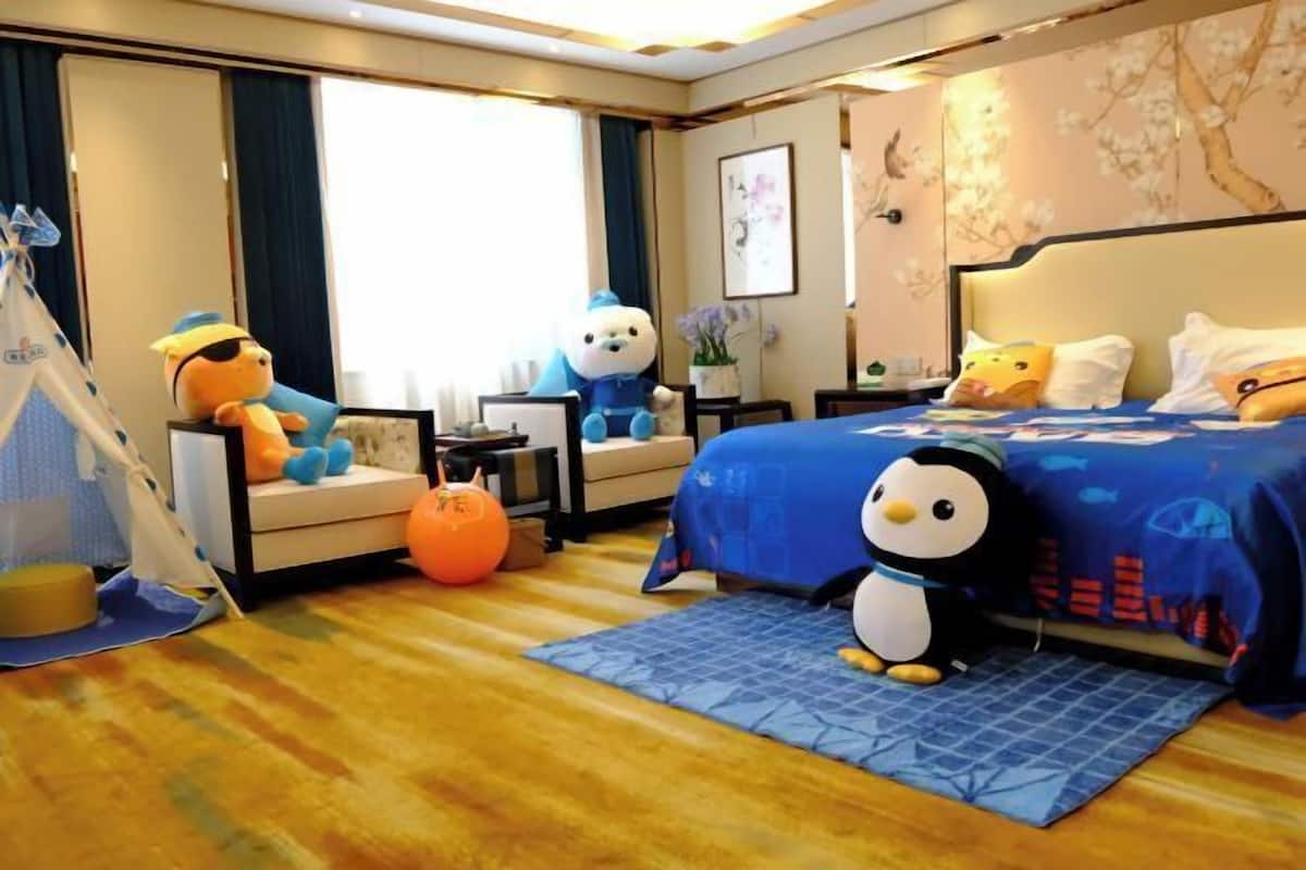 A hotel room with a bed, a sofa, a tent, and plush toys.