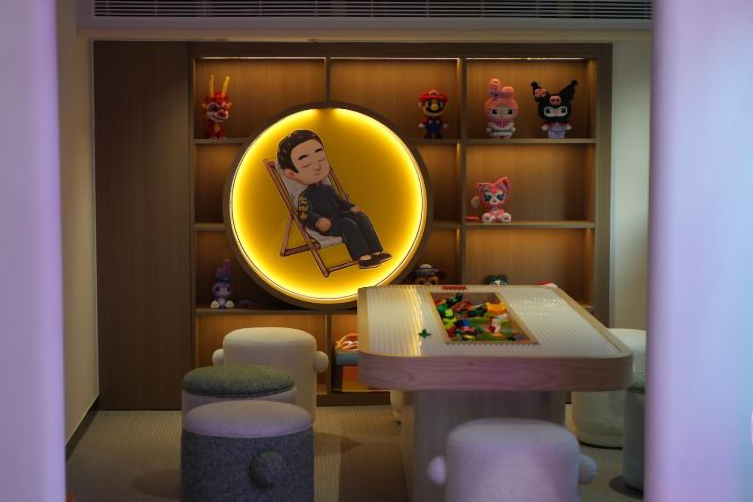 Une pièce avec un luminaire circulaire, une table avec des jouets et des étagères remplies de figurines.