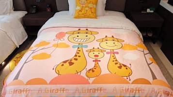A hotel room with a bed featuring a giraffe-themed bedspread, a nightstand with a lamp, and a bedside table with a phone.