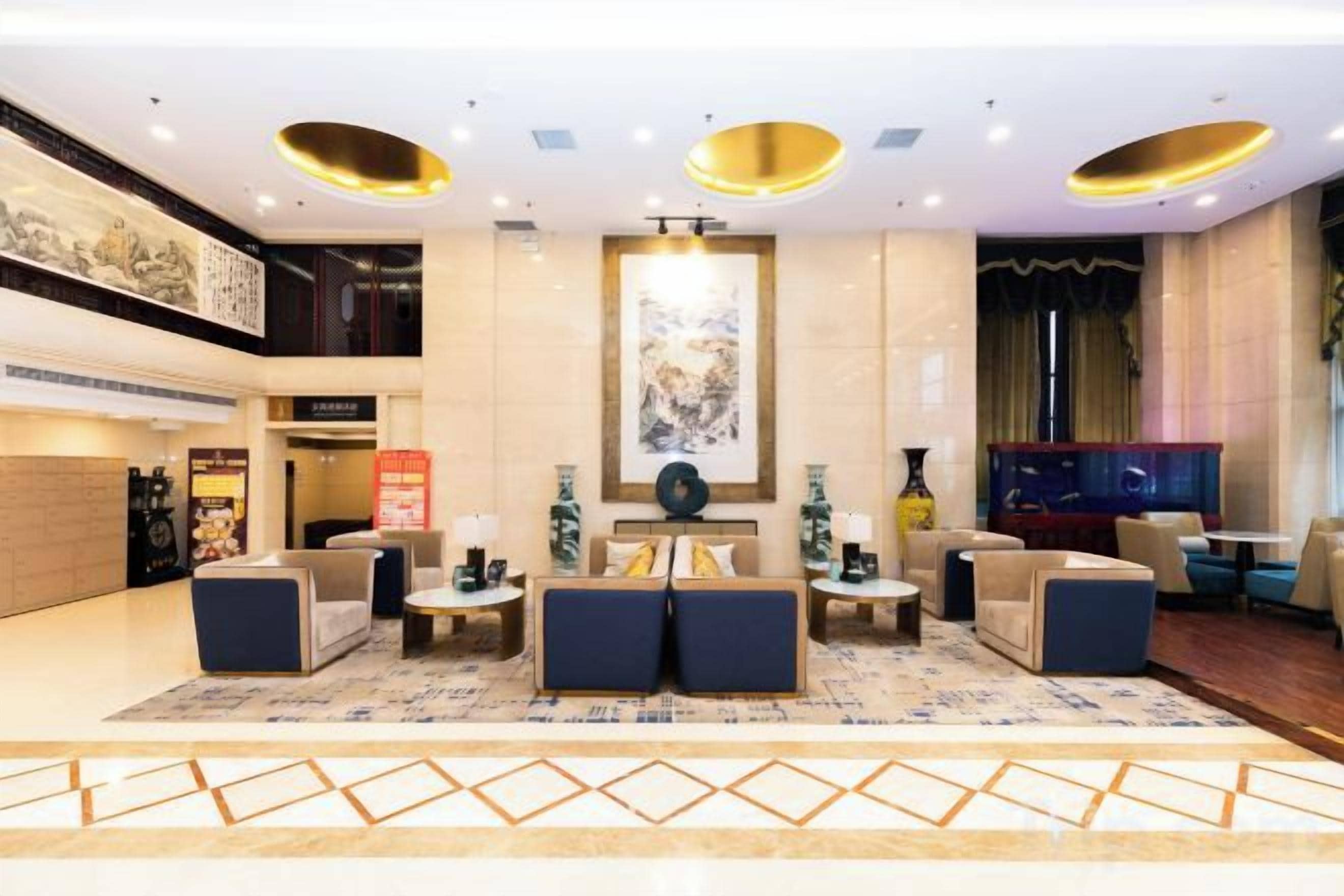 A spacious lobby with a central seating area, a large artwork on the wall, and a modern ceiling design.