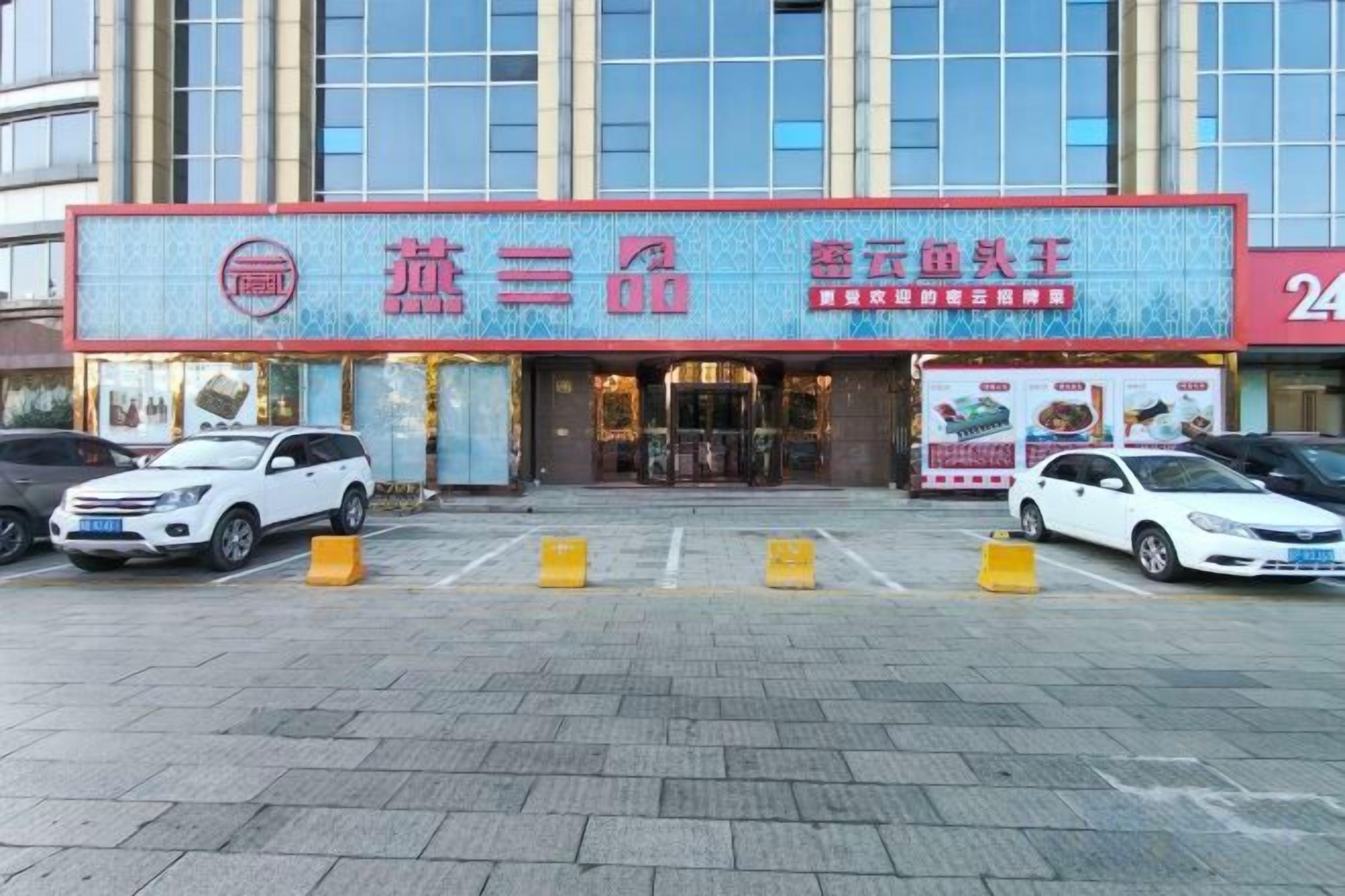 Un edificio con vetrina e insegna con caratteri cinesi, parcheggio auto e architettura moderna.