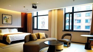 A modern hotel room with a bed, sofa, armchair, and a small table. - Beijing Jindilai Business Club (Yansai Outlets Miyun Branch) (Beijing)