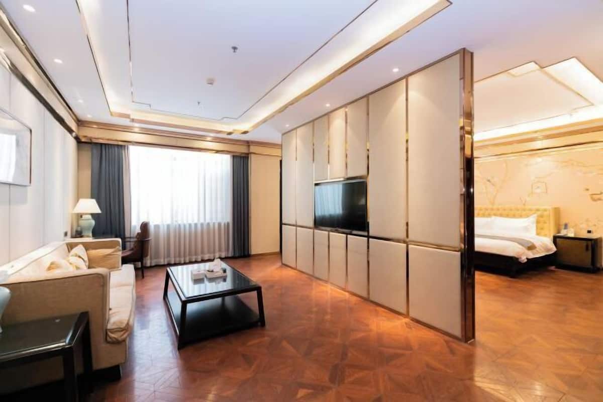 A modern hotel room with a sofa, a coffee table, a TV, and a bed.