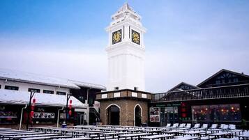 A clock tower, outdoor seating area, and buildings with signage.