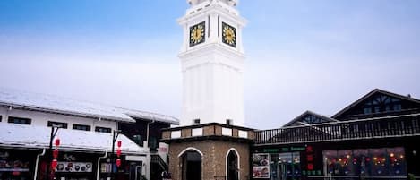 A clock tower, outdoor seating area, and buildings with signage.