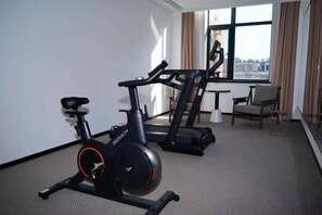 A hotel room with a stationary bike, a treadmill, and a view of the city through large windows. - Beijing Jindilai Business Club (Yansai Outlets Miyun Branch) (Beijing)