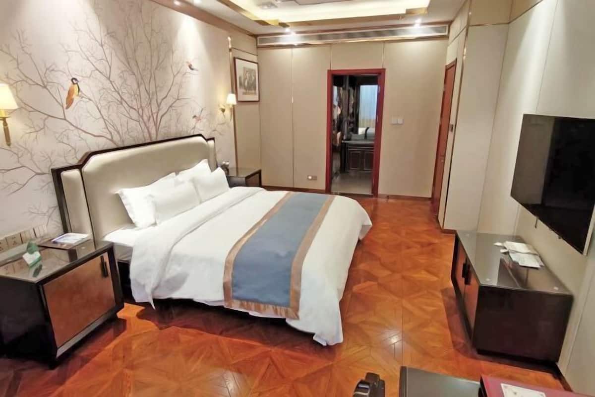 A hotel room with a bed, a TV, a desk, and a wardrobe.