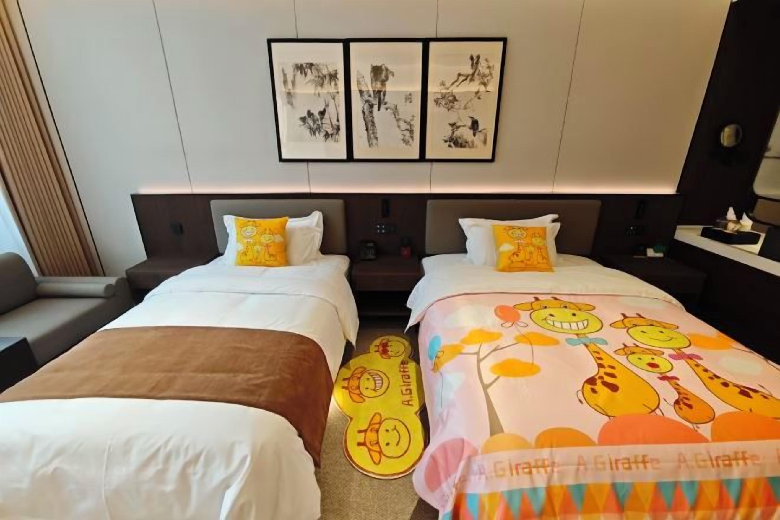 A hotel room with two beds, a sofa, and artwork on the wall.