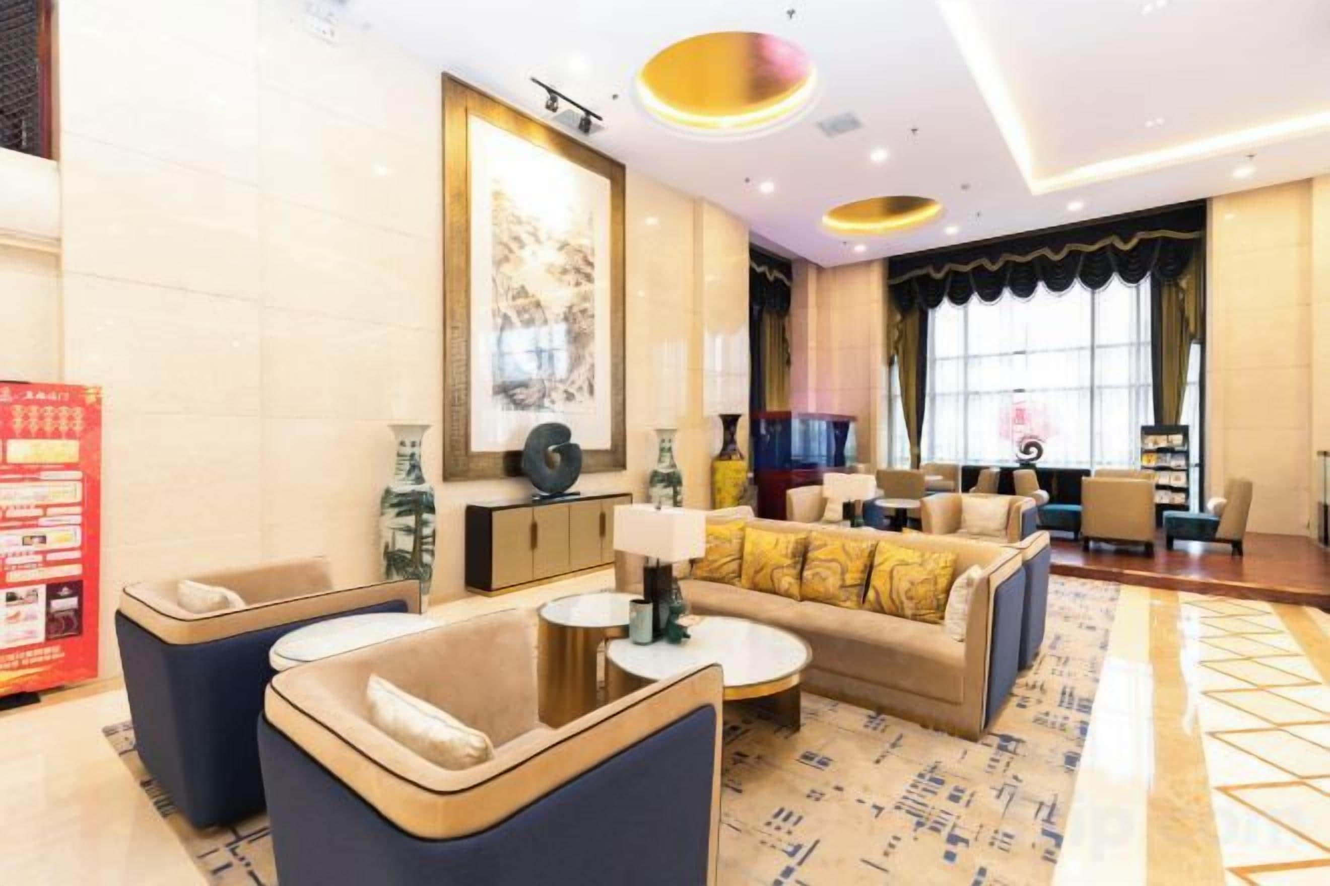 A modern hotel lobby with a sofa set, a coffee table, and a TV in the background.