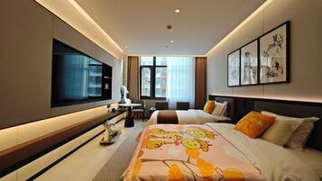 A modern hotel room with a large bed, a flat-screen TV, a desk with a chair, and artwork on the walls.
