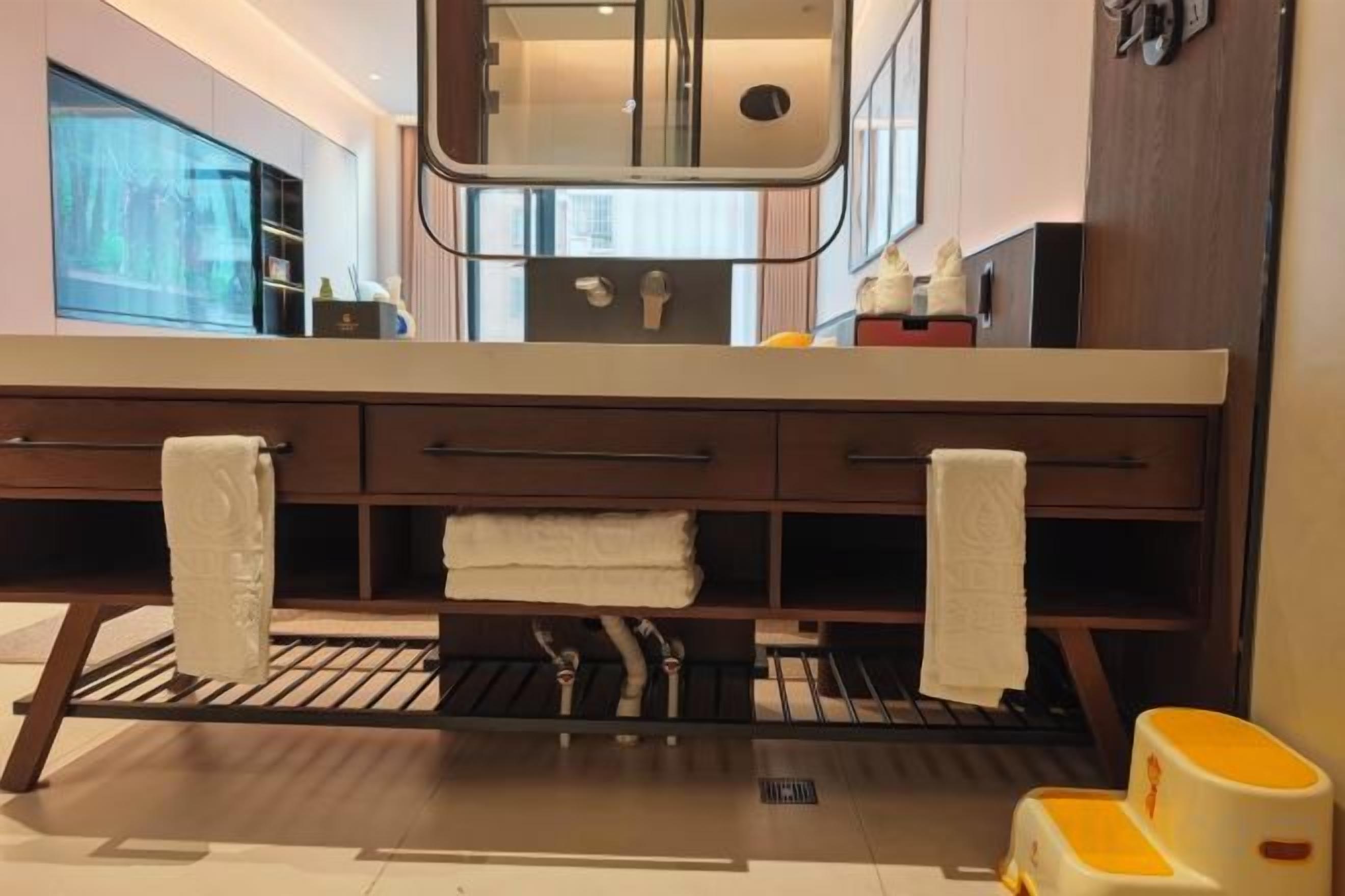 A modern bathroom with a large mirror, two towel racks, and a sink.