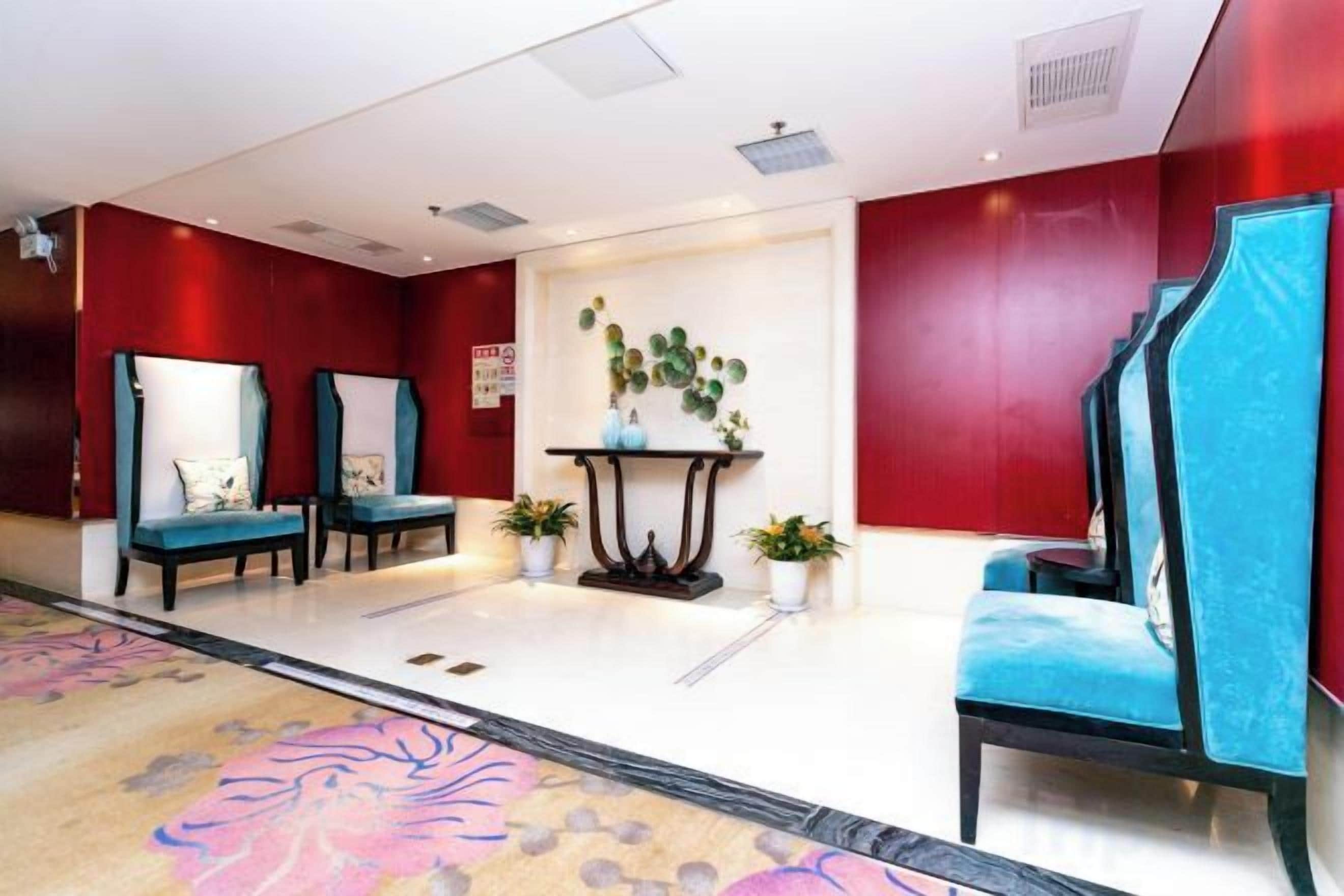 A hotel lobby with seating areas, a reception desk, and a decorative wall.