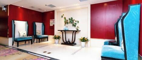 A hotel lobby with seating areas, a reception desk, and a decorative wall.
