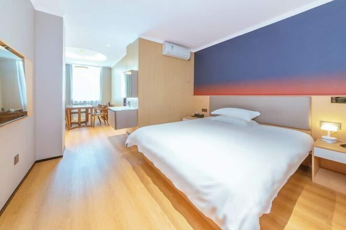 A hotel room with a large bed, a desk, and a chair.