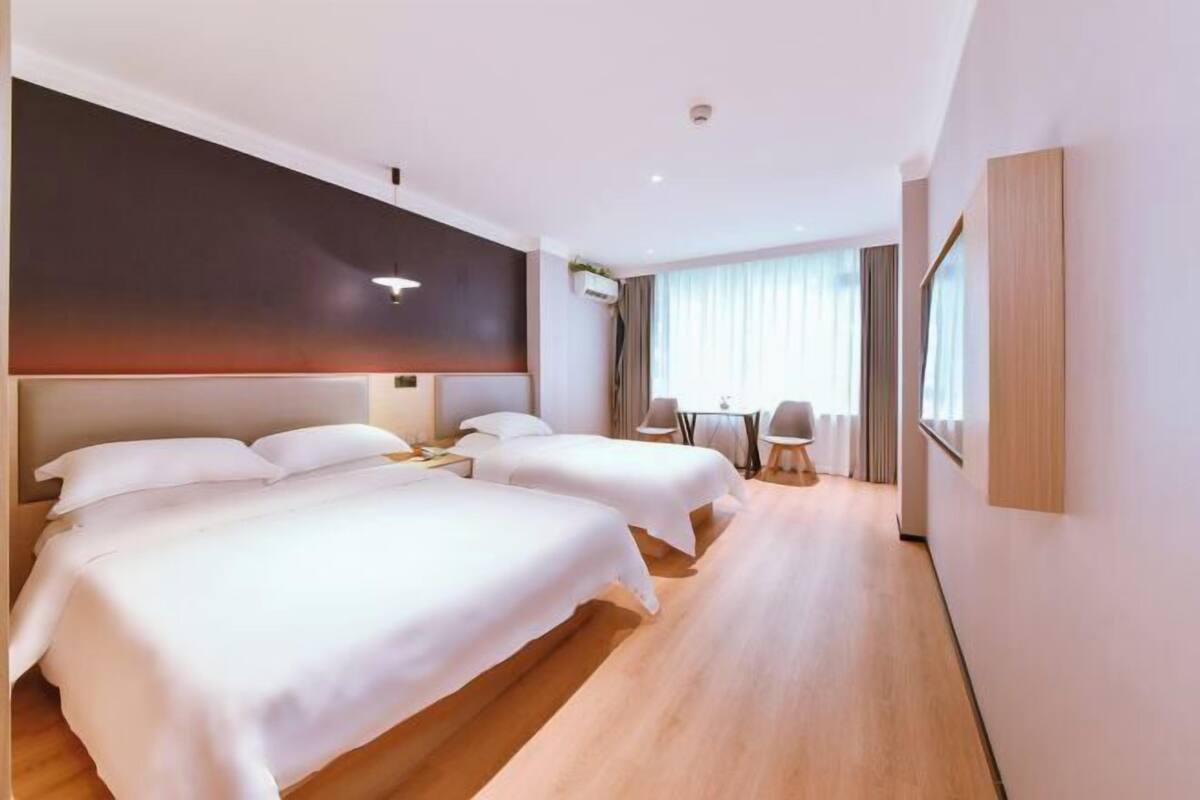 A hotel room with two beds, a desk, and a chair.